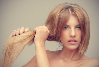Mujer rubia estirando su cabello reseco