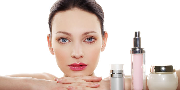 mujer con varios productos dermocosméticos y cosméticos